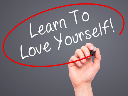 Man Hand writing Learn To Love Yourself with marker on transparent wipe board. Isolated on grey. Business, internet, technology concept. Stock Photoの写真素材