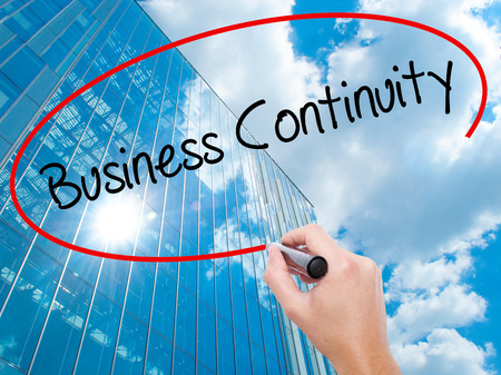 Man Hand writing Business Continuity with black marker on visual screen. Business, technology, internet concept. Modern business skyscrapers background. Stock Photoの写真素材