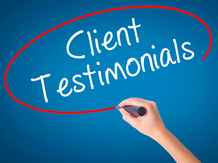 Women Hand writing Client Testimonials with black marker on visual screen. Isolated on blue. Business, technology, internet concept. Stock Photoの写真素材