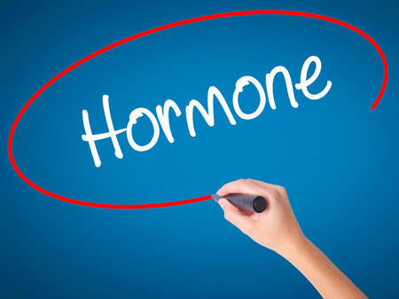 Women Hand writing Hormone with black marker on visual screen. Isolated on blue. Business, technology, internet concept. Stock Photoの写真素材