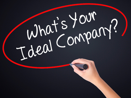 Woman Hand Writing Whats Your Ideal Company? on blank transparent board with a marker isolated over black background. Stock Photoの写真素材