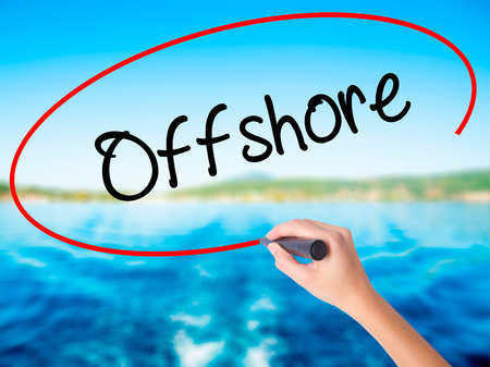 Woman Hand Writing Offshore on blank transparent board with a marker isolated over water background. Business concept. Stock Photoの写真素材