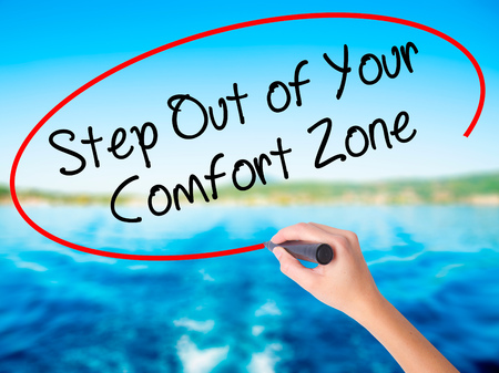 Woman Hand Writing Step Out of Your Comfort Zone on blank transparent board with a marker isolated over water background. Business concept. Stock Photoの写真素材