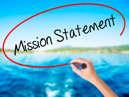 Woman Hand Writing Mission Statement on blank transparent board with a marker isolated over water background. Business concept. Stock Photoの写真素材