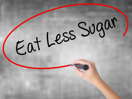 Woman Hand Writing Eat Less Sugar  with black marker over transparent board. Isolated on grey. Business concept. Stock Photoの写真素材