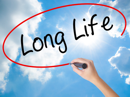 Woman Hand Writing Long Life with black marker on visual screen. Isolated on Sunny Sky. Business concept. Stock Photoの写真素材
