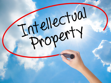 Woman Hand Writing Intellectual Property with black marker on visual screen. Isolated on Sunny Sky. Business concept. Stock Photoの写真素材