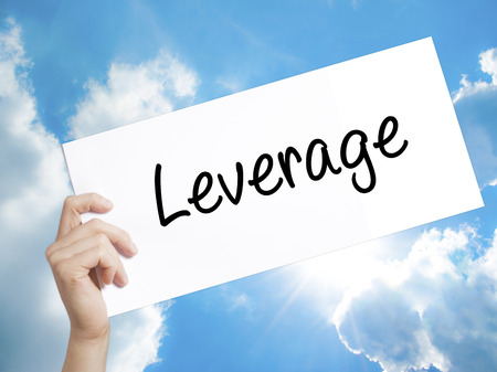 Man Hand Holding Paper with text Leverage . Sign on white paper. Isolated on Sky background.  Business concept. Stock Photoの写真素材