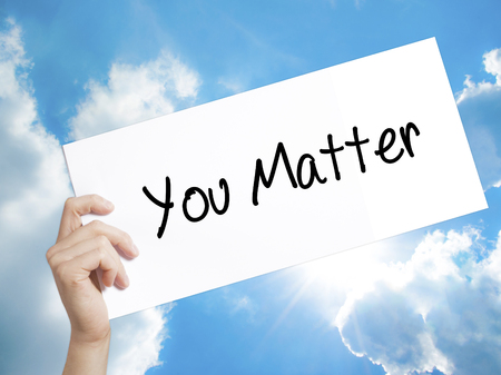Man Hand Holding Paper with text You Matter . Sign on white paper. Isolated on Sky background.   Business concept. Stock Photoの写真素材