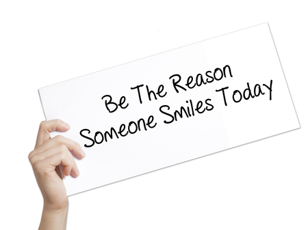 Paper with text Be The Reason Someone Smiles Today  . Man Hand Holding Sign on white paper. Isolated on white background.   Business concept. Stock Photoの写真素材