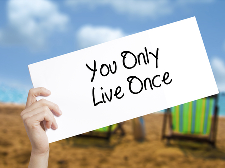 You Only Live Once Sign on white paper. Man Hand Holding Paper with text. Isolated on holiday background.  Business concept. Stock Photoの写真素材