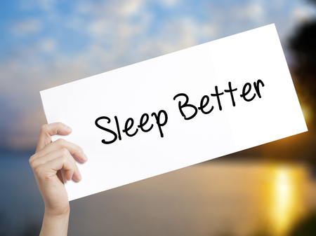 Sleep Better Sign on white paper. Man Hand Holding Paper with text. Isolated on sunset background.  technology, internet concept.の写真素材