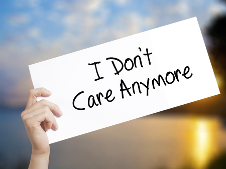 I Don't Care Anymore Sign on white paper. Man Hand Holding Paper with text. Isolated on sunset background.  Business concept. Stock Photoの写真素材