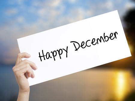 Happy December Sign on white paper. Man Hand Holding Paper with text. Isolated on sunset background.   Business concept. Stock Photoの写真素材