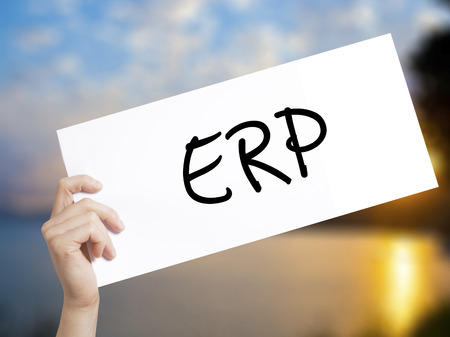 ERP (Enterprise Resource Planning)   Sign on white paper. Man Hand Holding Paper with text. Isolated on sunset background.  Business concept. Stock Photoの写真素材