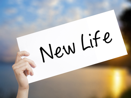 New Life Sign on white paper. Man Hand Holding Paper with text. Isolated on sunset background.  Business concept. Stock Photoの写真素材