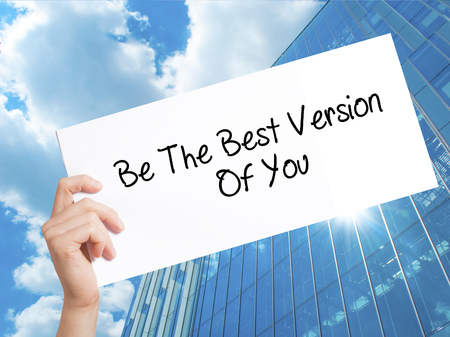 Be The Best Version Of You Sign on white paper. Man Hand Holding Paper with text. Isolated on Skyscraper background.   Business concept. Stock Photoの写真素材