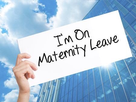 I'm On Maternity Leave Sign on white paper. Man Hand Holding Paper with text. Isolated on Skyscraper background.  Business concept. Stock Photoの写真素材