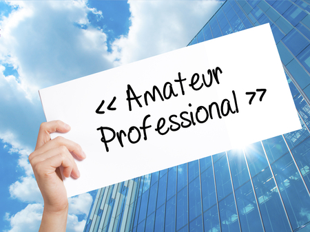 Amateur - Professional Sign on white paper. Man Hand Holding Paper with text. Isolated on Skyscraper background. Isolated on background. Business, technology, internet concept. Stock 
Photoの写真素材