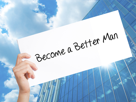 Become a Better Man Sign on white paper. Man Hand Holding Paper with text. Isolated on Skyscraper background.   Business concept. Stock Photoの写真素材