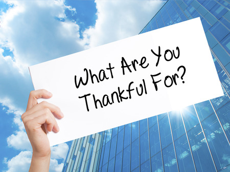 What Are You Thankful For? Sign on white paper. Man Hand Holding Paper with text. Isolated on Skyscraper background.  technology, internet concept.の写真素材