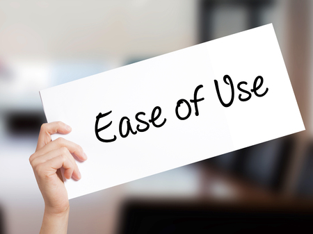 Ease of Use Sign on white paper. Man Hand Holding Paper with text. Isolated on Office background.  technology, internet concept.の写真素材