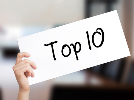 Top 10 Sign on white paper. Man Hand Holding Paper with text. Isolated on Office background.   Business concept. Stock Photoの写真素材