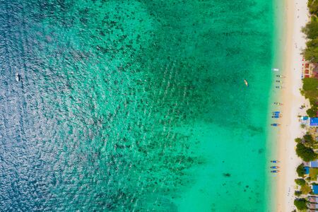 View from above, stunning aerial view of a beautiful tropical beach with white sand and turquoise clear water, long-tail boat and people sunbathing,Long beach, Phi Phi Thailand.の写真素材