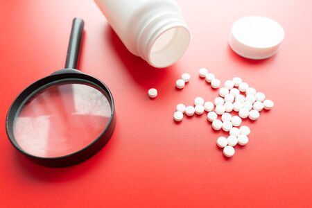 Medical, medicine stethoscope and pills on red background. Health care or illness. Tablet or drug in hospital or pharmacy. Cardiology heart treatment. Medication prescriptionの写真素材