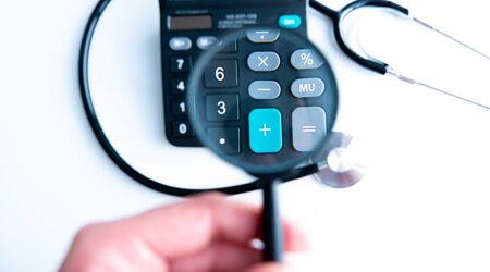 Selective focus Health care concept. Stethoscope on a calculator with Magnifying glass with effect...