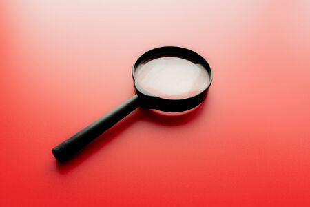 Close up Single Magnifying Glass with Black Handle, Leaning on the red Table at the Office.の写真素材