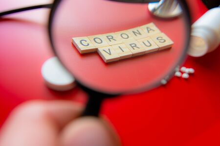 Coronavirus COVID-19 concept image wit text seen through a magnifying glass. Red Backgroundの写真素材
