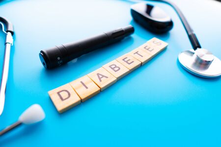 Wooden text Diabetes. Diabetes concept. Syringe, Glucometer or Glucose meter and stethoscope on pink background. Healthcare, Medical and copy spaceの写真素材