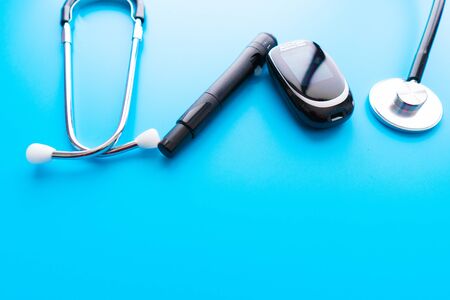 Medicine, Diabetes, Glycemia, Health care and people concept - close up of lancelet, Glucose meter and stethoscope on gray background.の写真素材