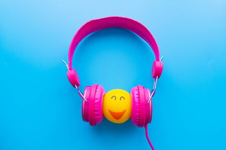 Top view the cup of coffee is listening music by pink headphones  on blue backgroudn with copy space.の写真素材