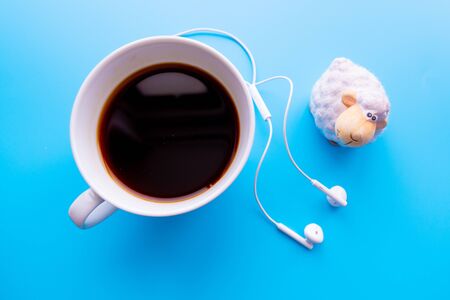 Headphones and coffee cup on blue desk table. Music concept. Top view with copy spaceの写真素材