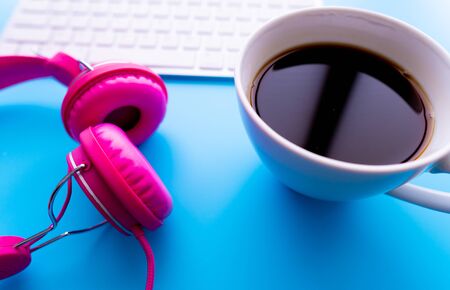 Top view the cup of coffee is listening music by pink headphones  on blue backgroudn with copy space.の写真素材