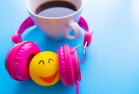 Top view the cup of coffee is listening music by pink headphones  on blue backgroudn with copy space.の写真素材