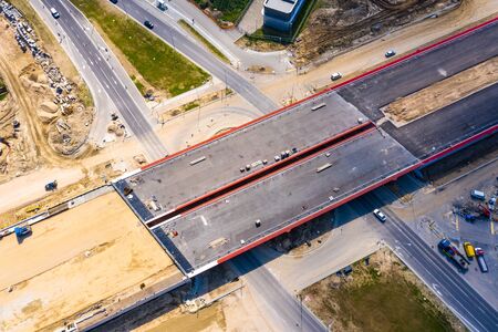 Aerial panorama top down view of an unfinished asphalt covered road with dirt, tracks of heavy...