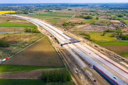 Aerial panorama top down view of an unfinished asphalt covered road with dirt, tracks of heavy...