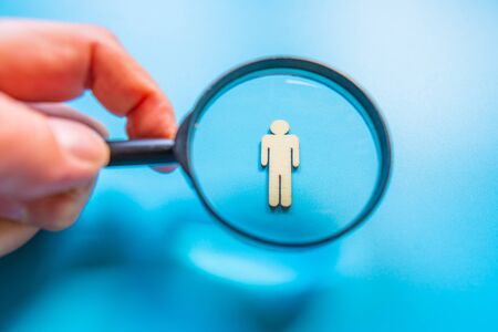 Employee search HR concept - magnifier with abstract employee on a blue background. Close up.の写真素材