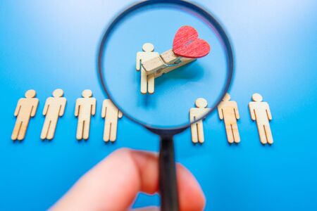 The chosen person among others. A human figure of wooden stands out from the crowd. Wooden figures of people. A talented worker, a successful choice. Promotion. Concept of search for worker.の写真素材