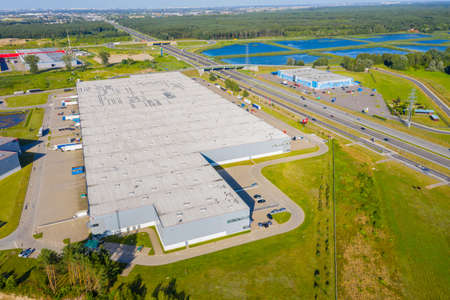Aerial Top View of Industrial Storage Building Area with Solar Panels on the Roof and Many Trucks Unloading Merchandise.の写真素材