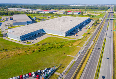 Aerial Top View of Industrial Storage Building Area with Solar Panels on the Roof and Many Trucks Unloading Merchandise.の写真素材