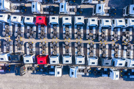Lots of freight trailers. Cars are in several rows. Truck parking. Aerial view vertically down.