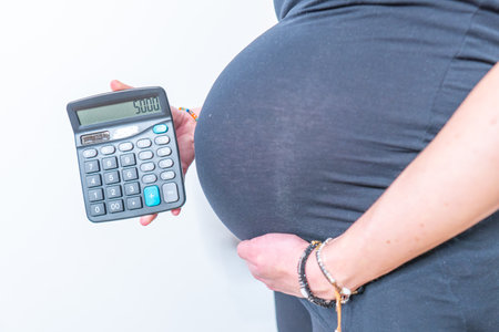 Pregnant woman holding calculator expenditure figures show isolated on white backgroundの写真素材