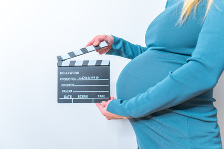 Pregnant woman hands holding clapper board on her bellyの写真素材