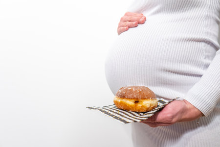 Happy pregnant woman with Christmas gift box on bed at home, closeup. Expecting babyの写真素材