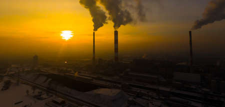 Power Plant emissions seen above the city during sunrise. Environmental pollution. Factory pipe polluting air.Panorama sunset. Smoking pipes Aerial view,の写真素材