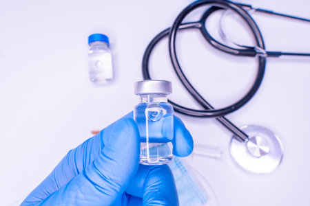 flu and pandemic vaccines, syringe and vial with red liquid on a blue background. medical concept,...